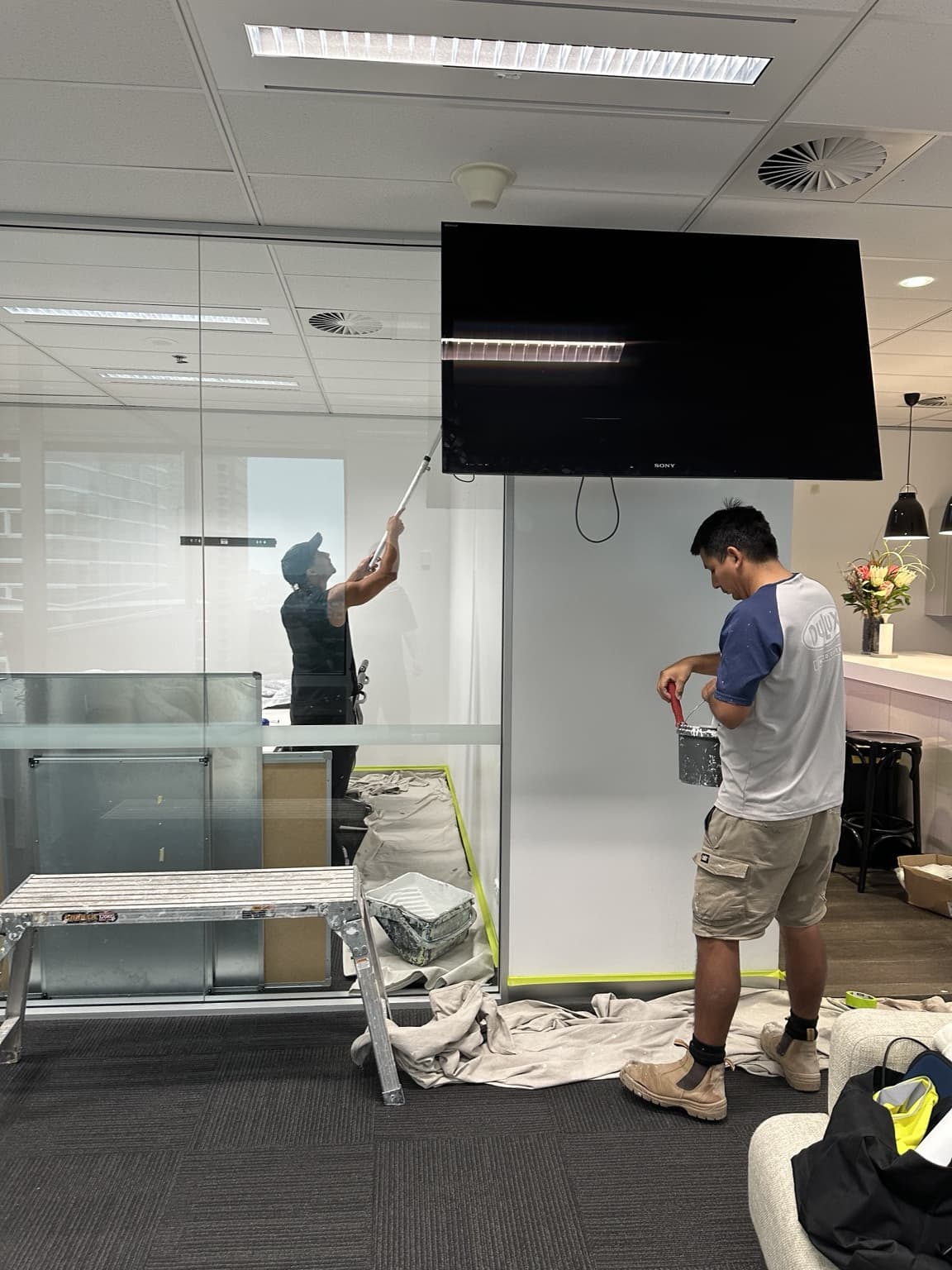 Trade painters actively painting and cutting in walls in Sydney CBD tenancy